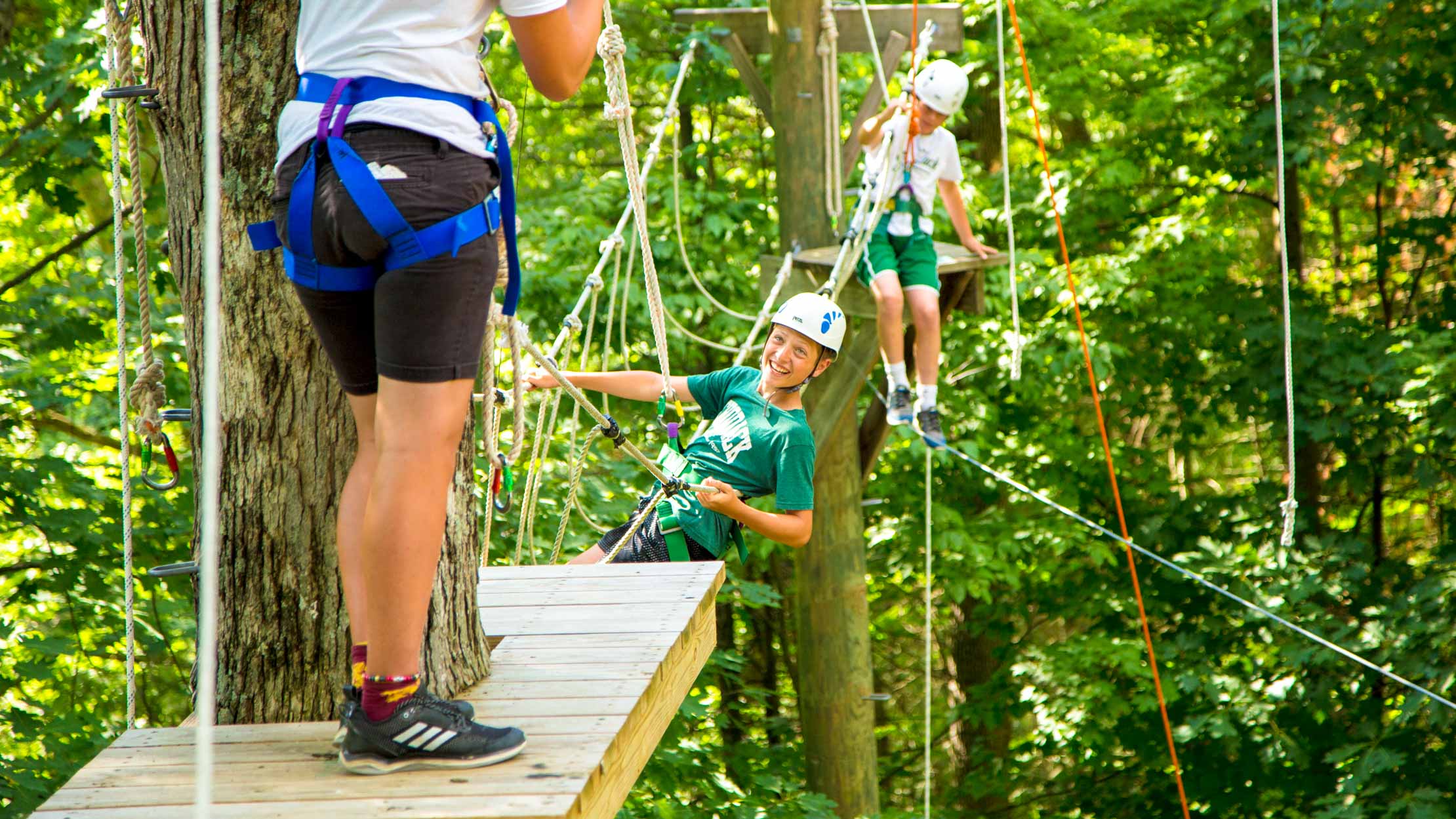 Smiling camper hangs on high ropes course